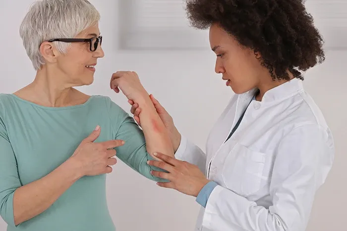 A doctor is examining an older woman's arm.